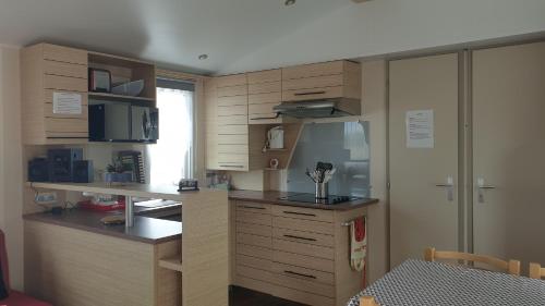 - une cuisine avec des placards en bois et un comptoir dans l'établissement Sylvie propriétaire du mobil-home " Camping de la Chanterie", à Saint-Pair-sur-Mer