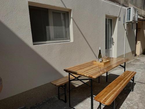 a wooden table with a bottle of wine and two benches at Secret Place Apartment in Stari Grad