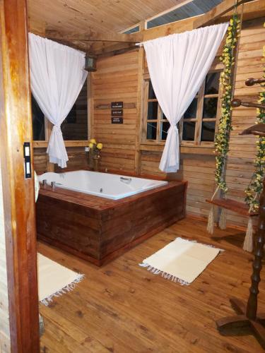Chalés da Serra Catarinense في بوم جارديم دا سيرا: حوض استحمام في غرفة مع أرضيات خشبية