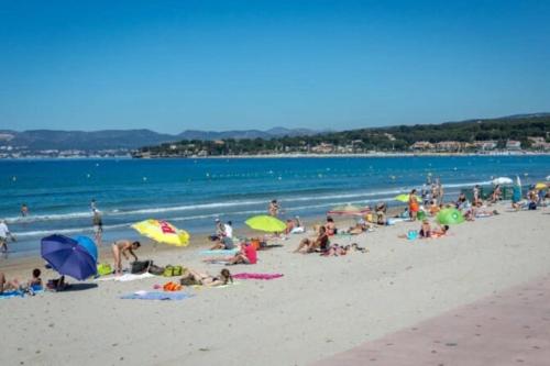 un groupe de personnes sur une plage avec des parasols dans l'établissement Plage & Soleil, Charmant Studio 5 minutes à pied du port et de la plage, à Saint-Cyr-sur-Mer