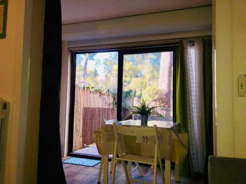 une table et des chaises devant une grande fenêtre dans l'établissement Plage & Soleil, Charmant Studio 5 minutes à pied du port et de la plage, à Saint-Cyr-sur-Mer