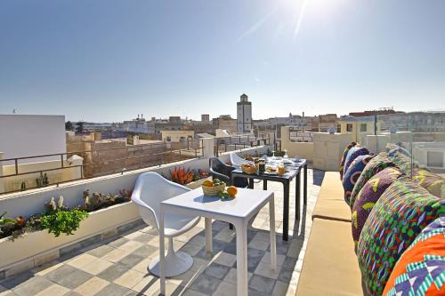 a balcony with tables and chairs on a roof at Riad EspritBleu - Adult Only in Essaouira