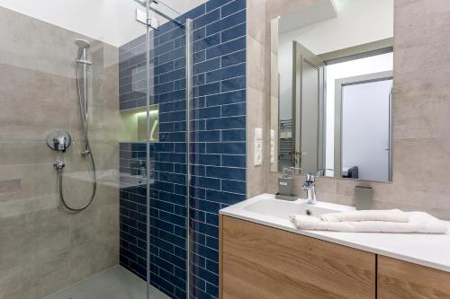 a bathroom with a sink and a shower with blue tiles at Alder Bridge Apartment in Budapest