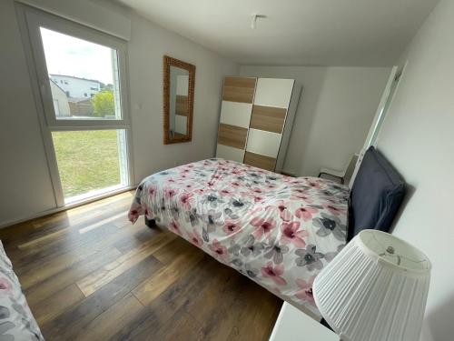 een slaapkamer met een bed met een bloemenbed en een raam bij Logement pour 6 personnes 800 m des plages in Saint-Pabu
