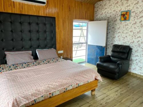 a bedroom with a large bed and a black leather chair at Charming 2 Bedroom Rustic Villa with Garden in Lansdowne