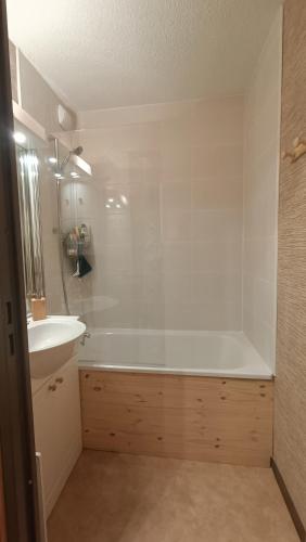 une salle de bain avec une baignoire blanche et un lavabo dans l'établissement Appartement pied des pistes - Samoëns 1600, à Samoëns