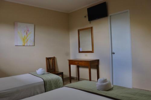 a room with two beds and a mirror and a table at Hotel Residencial Panamericano in David