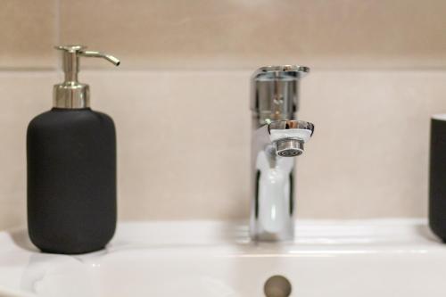 a bathroom sink with a soap dispenser and a black bottle at Gajeva Rooms - Malmö apartment SELF CHECK-IN in Virovitica