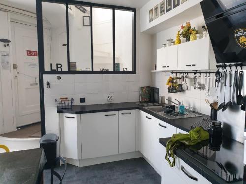 une cuisine avec des armoires blanches et des comptoirs noirs dans l'établissement Maison sur le quai, à La Rochelle