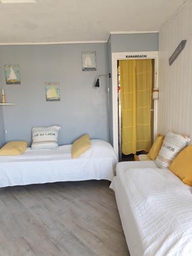 Cette chambre comprend 2 lits et une porte jaune. dans l'établissement Maison sur le quai, à La Rochelle