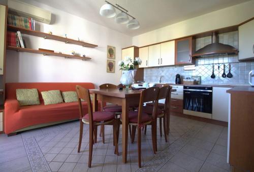 uma cozinha com uma mesa e cadeiras e um sofá vermelho em La casa di Noemi em Tempio Pausania