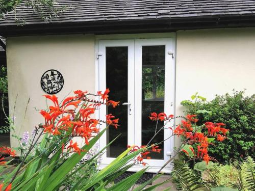 uma porta da frente de uma casa branca com flores vermelhas em Canalside Cottage em Barton under Needwood