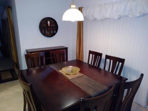 a dining room table with chairs and a clock on the wall at Amore's luxurious 4 bedroom home. in Kissimmee