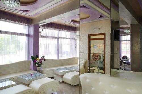 a living room with white furniture and large windows at Kalina Family Hotel in Burgas