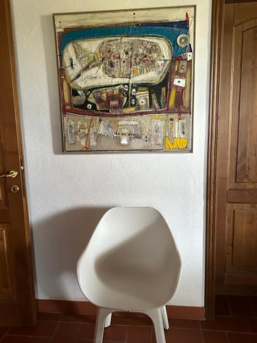 een witte stoel in een kamer met een schilderij aan de muur bij casaluna in Suvereto