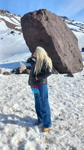 a young girl standing in the snow in front of a rock at Alojamiento Quincho Pascual in Las Compuertas