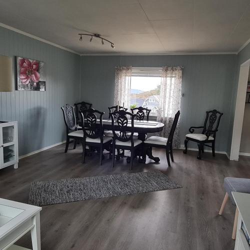 a dining room with a table and chairs at Koselig hus med hage i Herøy på Sunnmøre. in Røyra