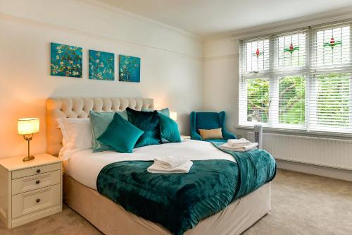 a bedroom with a large bed and two windows at Just Stay Wales - Highmead House, Swansea 