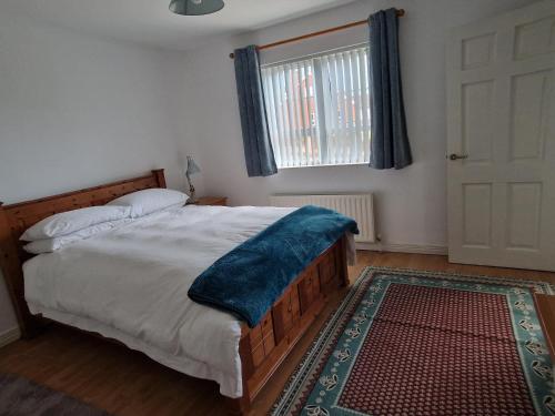 a bedroom with a bed with a blue blanket on it at Tirquin House in Omagh