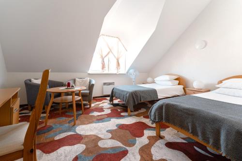 a bedroom with two beds and a table and a chair at Hermannuse Maja in Haapsalu