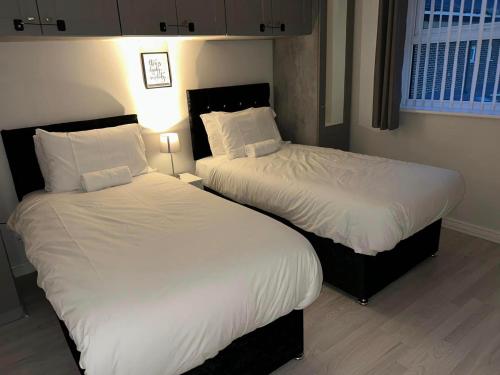duas camas num quarto de hotel com lençóis brancos em Sunderland City Centre Modern 2 Bed Apartment em Sunderland