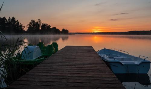 Sucha Rzeczka的住宿－Sielska Przystań，日落时分在湖上停泊两艘船的码头