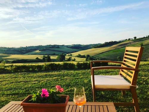 stół z krzesłem oraz kieliszek wina i kwiaty w obiekcie Il Giardino nella Valle w mieście Belvedere Ostrense