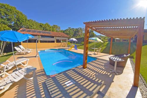 einen Pool mit Stühlen und Sonnenschirmen im Hof in der Unterkunft Chácara condomínio perto de SP in Ibiúna