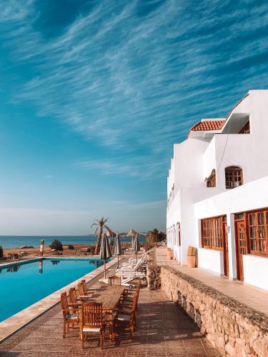 un complejo con piscina, mesas y sillas en Serenity Lodge, en Sharm El Sheikh