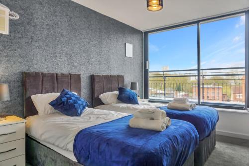 two beds in a bedroom with a large window at Penthouse With City Skyline Views - Free Parking - Balcony - King Size Bed - Netflix in Birmingham