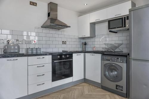a kitchen with white cabinets and a washer and dryer at Penthouse - Amazing City Skyline Views - Free Parking - Balcony - Utilita Arena - New St Station - Bullring Shopping in Birmingham