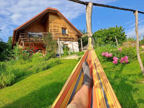 a person laying on a hammock in front of a house at Holiday Home Trnavsko in Bogojina