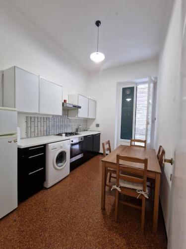 a kitchen with a table and a washing machine at Appartamento nuovo, appena arredato in Genoa