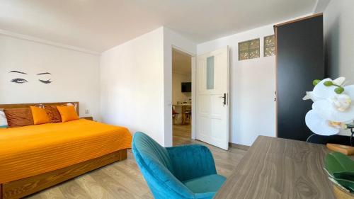 a bedroom with a bed and a blue chair and a table at WELL Prettyplaces Apartment 001 in Braşov