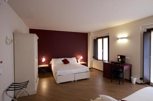 a hotel room with a bed and a desk and two windows at Hotel Leon D'Oro in Mantova