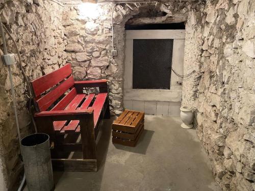 a red bench in a stone room with a window at Casa di Vincenzo in Airole