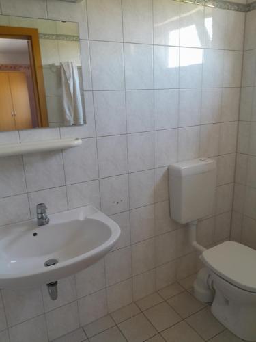 a white bathroom with a sink and a toilet at Sport & Freizeit Centrum Pension in Heudeber