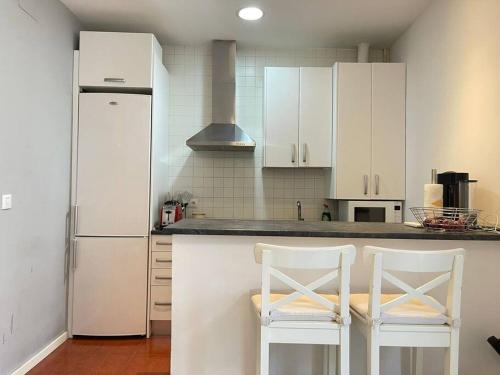 a kitchen with white cabinets and two white chairs at Piso en pleno centro de Madrid in Madrid