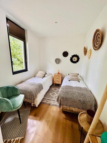 - 2 lits dans une chambre avec une chaise et une fenêtre dans l'établissement Lodge avec spa au coeur de Brocéliande, à Beignon