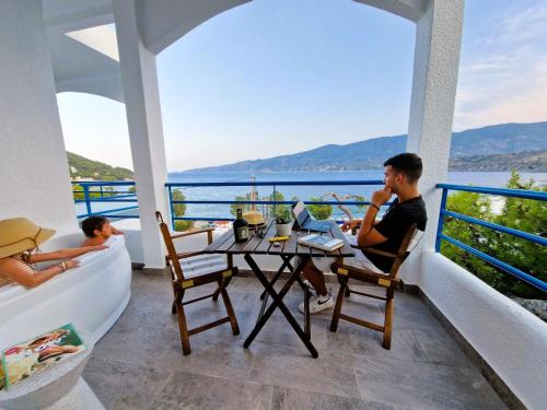zwei Personen sitzen an einem Tisch auf dem Balkon eines Hauses in der Unterkunft Christine Studios in Poros