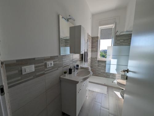 a white bathroom with a sink and two toilets at Holiday House in Villamagna