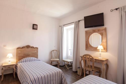 une chambre avec deux lits, un miroir et une fenêtre dans l'établissement Hôtel de la Plage Les Arcades, à Algajola