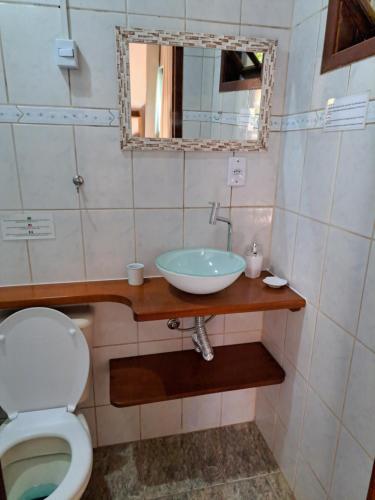 a bathroom with a sink and a toilet and a mirror at Recanto das Flores Lofts - Ilha Grande Rj in Abraão