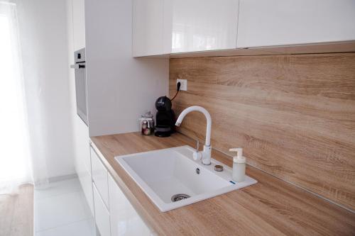 a white sink in a kitchen with a wooden wall at Rina Apartment- with barbecue and free parking in Kaštela