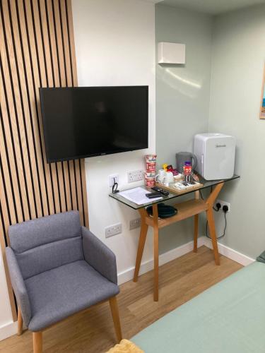 a room with a desk and a chair and a television at Central ensuite guest unit with free parking in Brighton & Hove