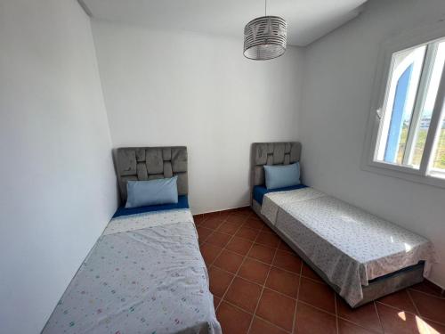 two beds sitting in a room with a window at Un bel appartement à Mirador Golf 2 in Cabo Negro