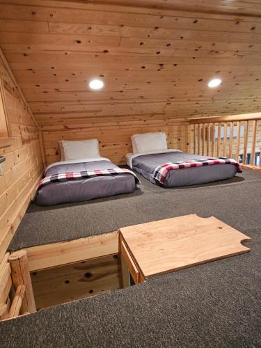 two beds in a log cabin with a table at Grandpa's Cabin in Apple Valley