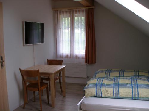 ein Schlafzimmer mit einem Tisch, einem Bett und einem Fenster in der Unterkunft Gasthof Rössli in Wyssachen