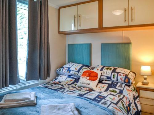 a bedroom with a bed with blue sheets and a window at Wildhaven Lodge in Dalbeattie
