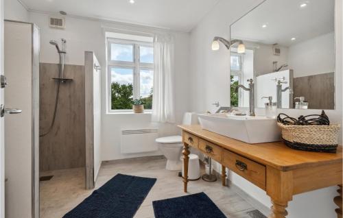 La salle de bains est pourvue d'un lavabo, de toilettes et d'un miroir. dans l'établissement Amazing Apartment In Svaneke With Wifi And 2 Bedrooms, à Svaneke